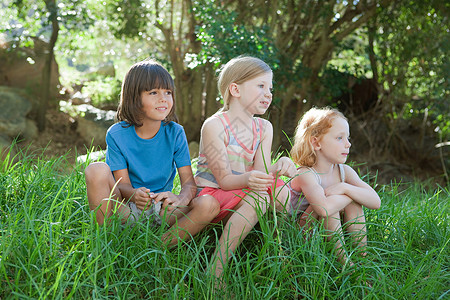 三个孩子坐在草地上自然高清图片素材