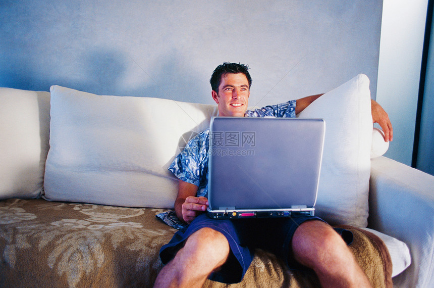 在沙发上用笔记本电脑的男人图片