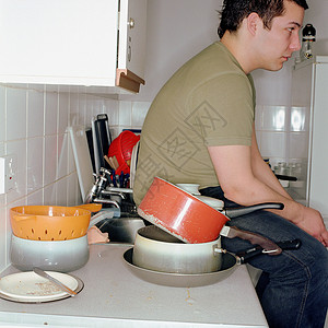 男孩坐在凌乱的厨房里图片