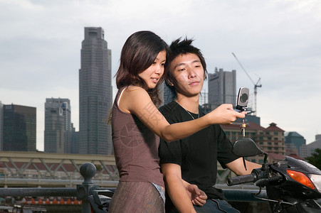 年轻夫妇使用手机拍照背景图片
