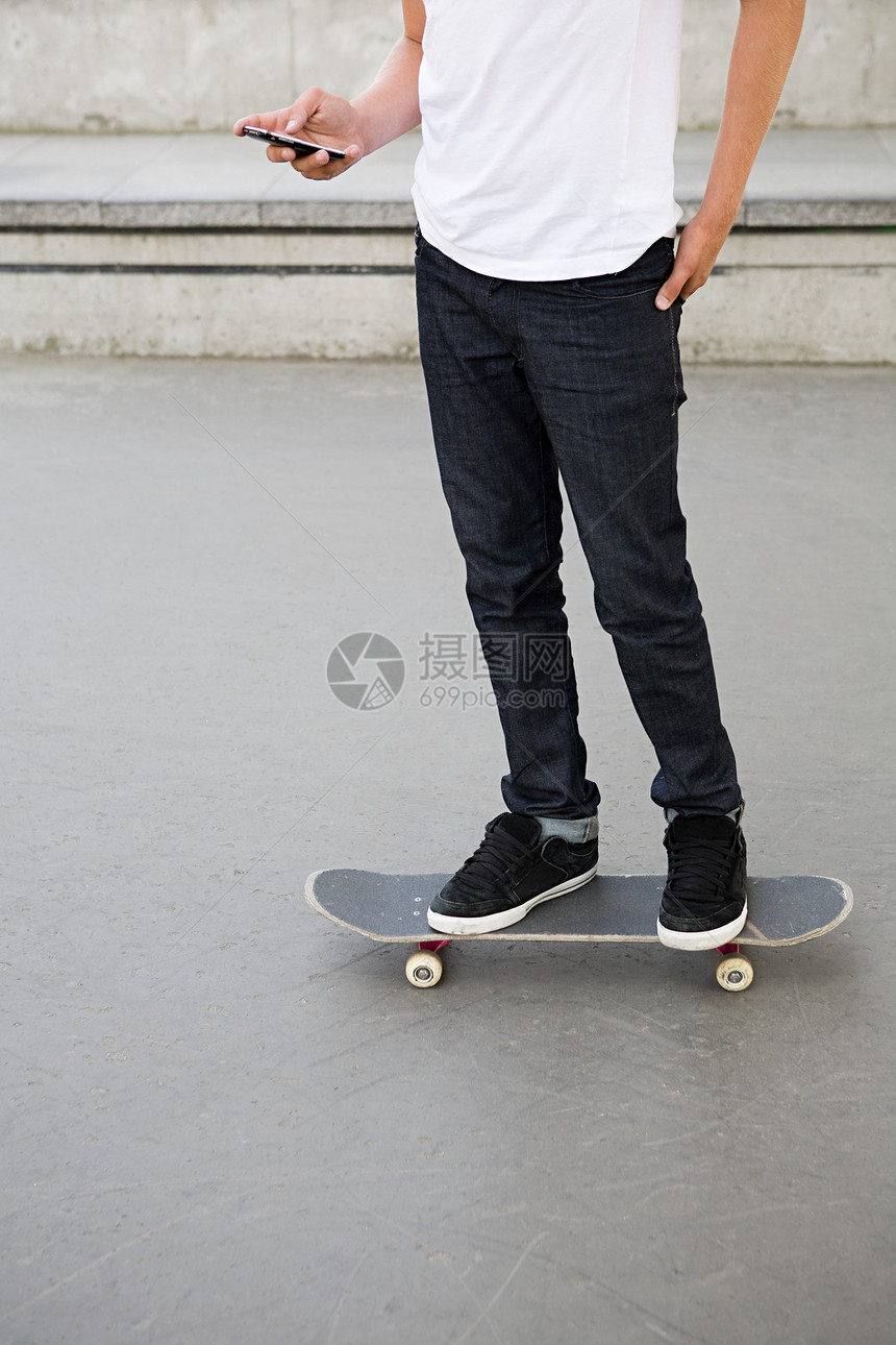 滑滑板玩手机的男孩图片