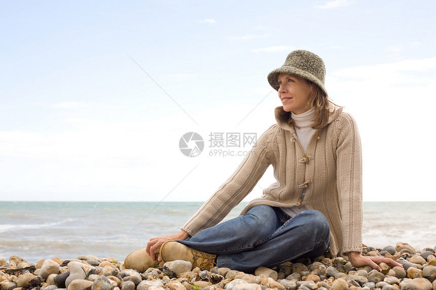 坐在卵石滩上的女人图片