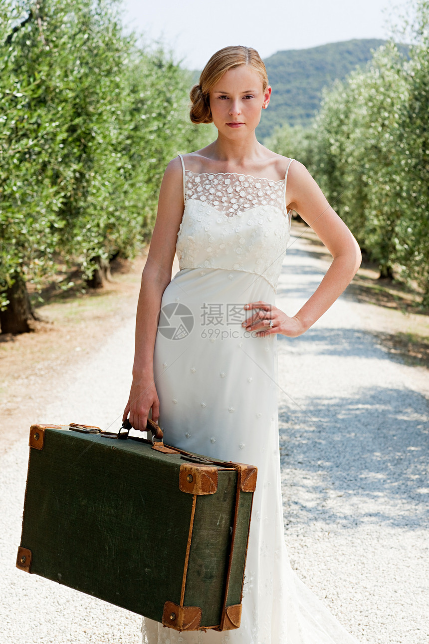 新娘带着手提箱在乡间小路上图片