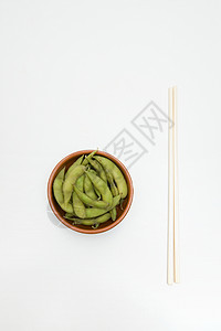 毛豆夹在盘子和筷子里豆荚高清图片素材