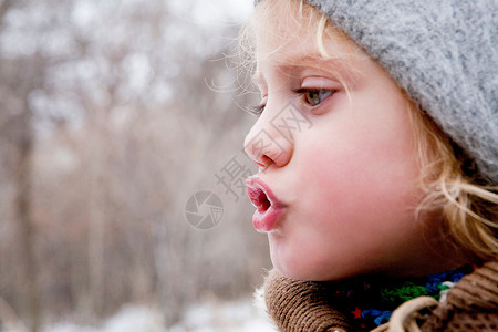 小女孩在寒冷的空气中看着她的呼吸背景图片