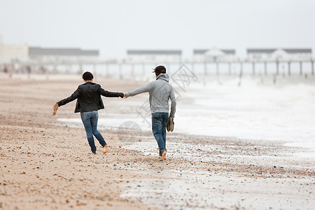一对夫妻在海边携手奔跑图片