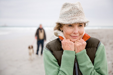 海滩上的女人，背景中的男人和狗图片