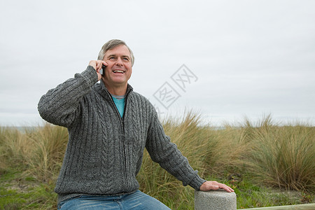 在海边拿着智能手机的男人图片