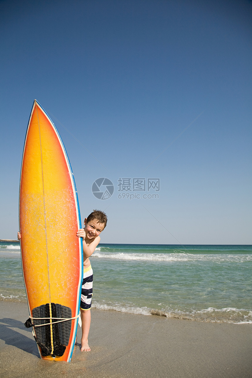 男孩把冲浪板放在沙子里图片