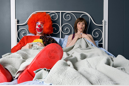 小丑和女人惊奇地发现他们在床上在一起背景图片