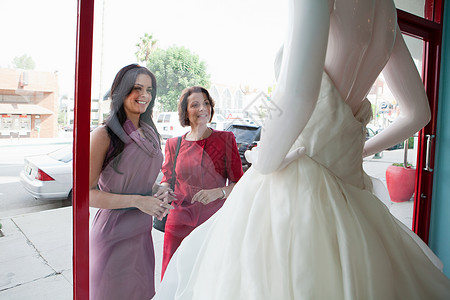 婚纱橱窗妈妈和女儿在商店橱窗里看婚纱背景