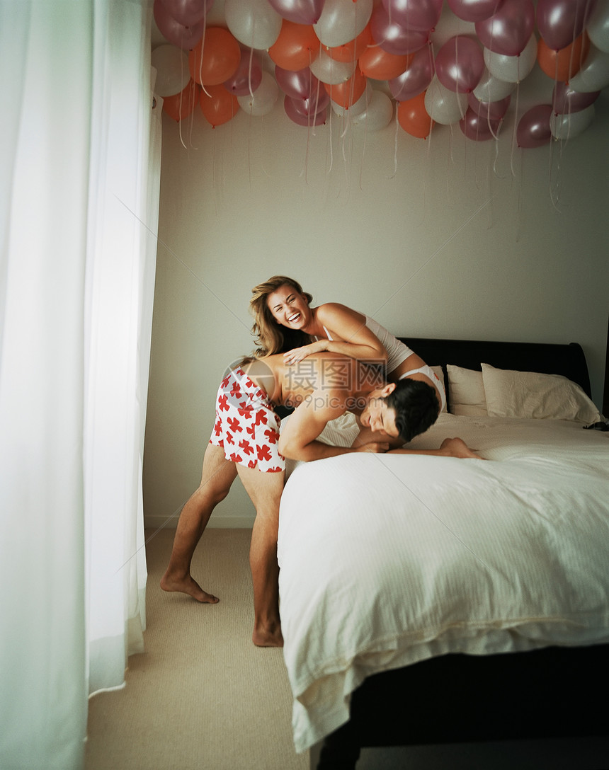 夫妇微笑着在床上摔跤图片