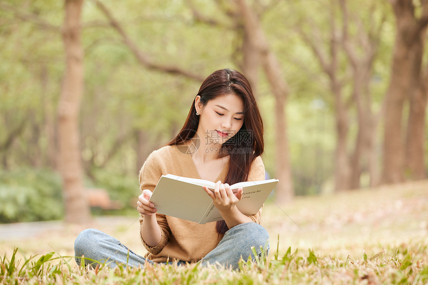 年轻女性坐在草地上看书 图片