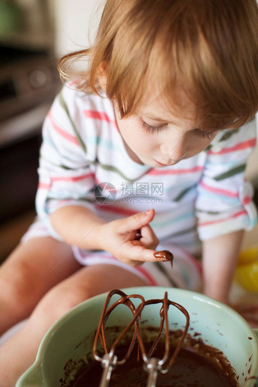 女孩在厨房品尝蛋糕糊图片
