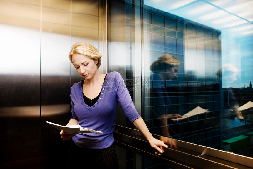 电梯里的女人，正在读文件图片
