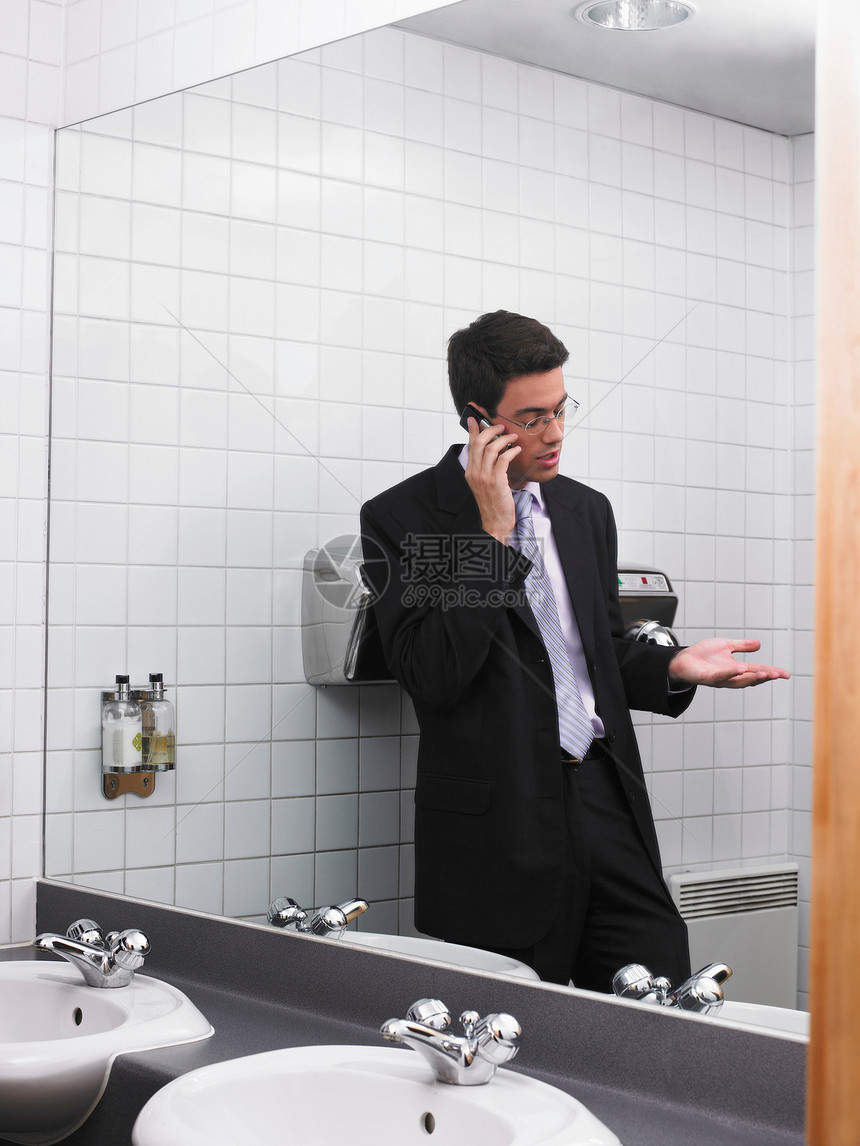 用手机反射在办公室卫生间镜子里的男人图片