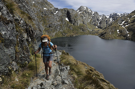 在新西兰山区的小路上徒步旅行的女人图片