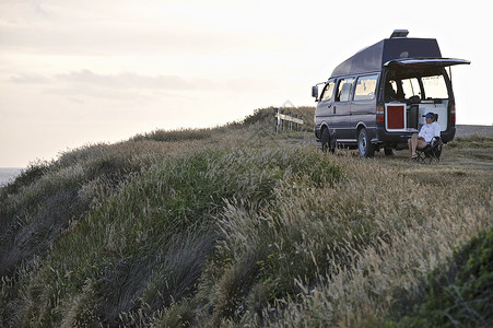 一个人的旅游坐在露营车旁的妇女，新西兰背景