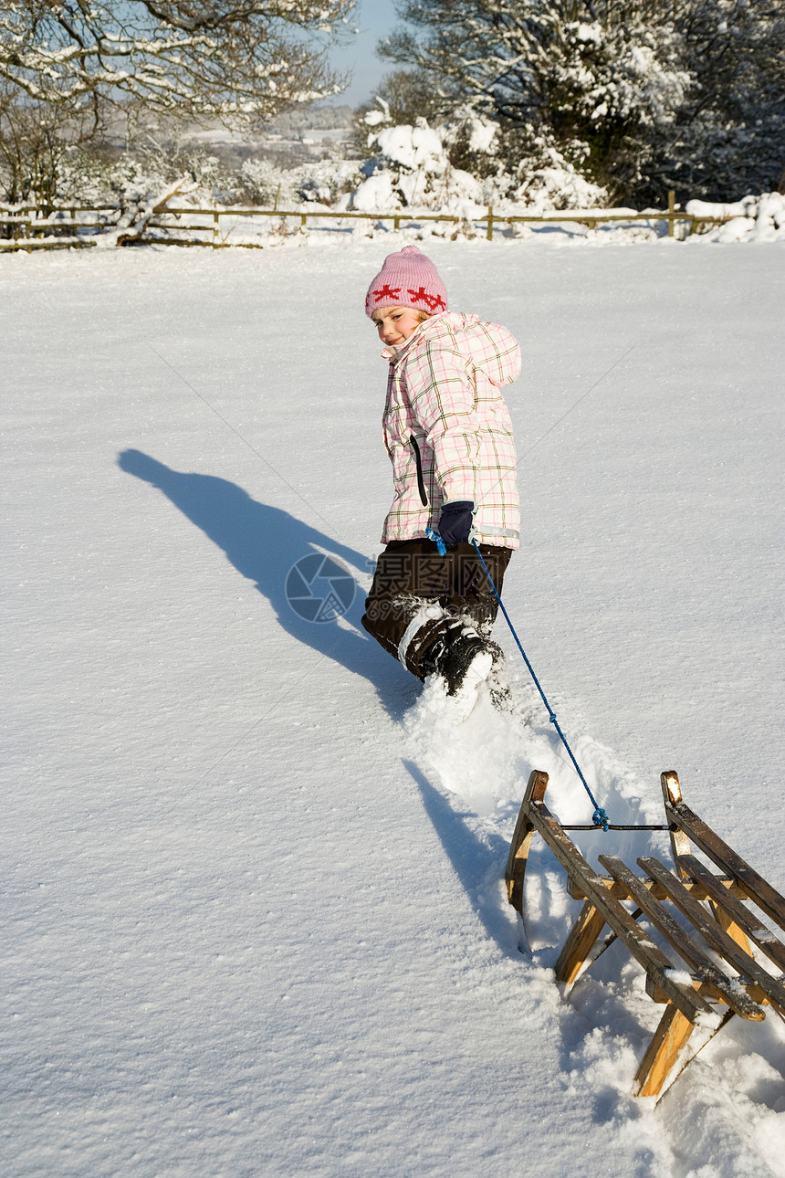 在雪地里拉雪橇的小女孩图片