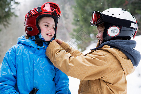 小男孩帮女孩戴滑雪的头盔图片