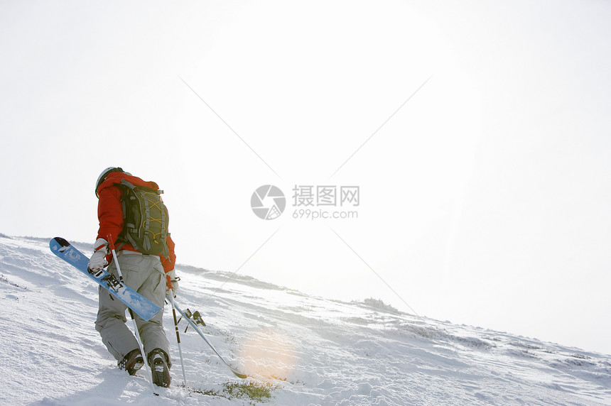 带着滑雪板上坡的人图片