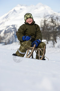 坐在雪橇上的男孩图片