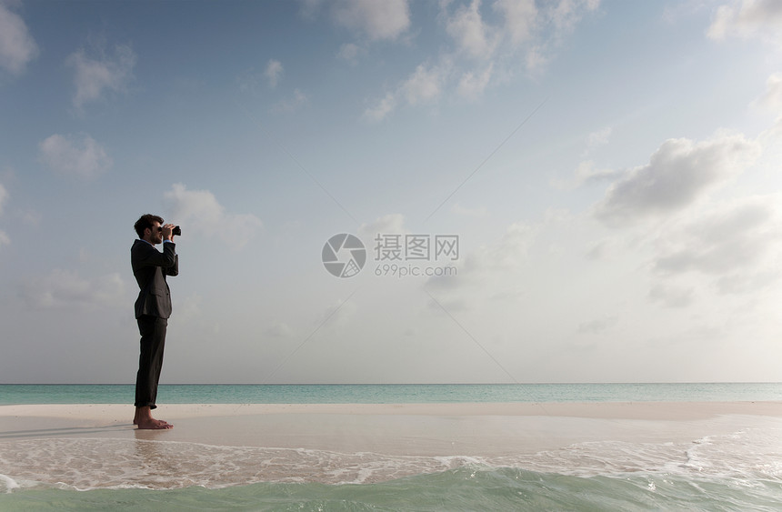 商人在海滩上用望远镜图片