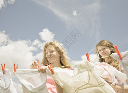 女孩们在晾衣绳上搭衣服家务活高清图片素材