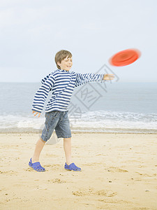 男孩在海滩上扔飞盘图片