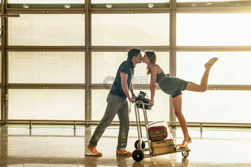 带行李车的年轻夫妇在机场接吻图片
