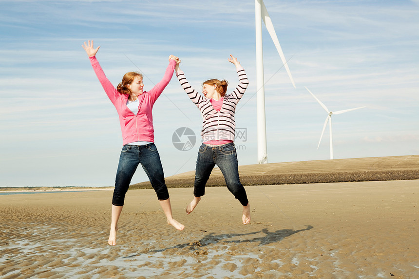 两个女孩在海滩上跳跃图片