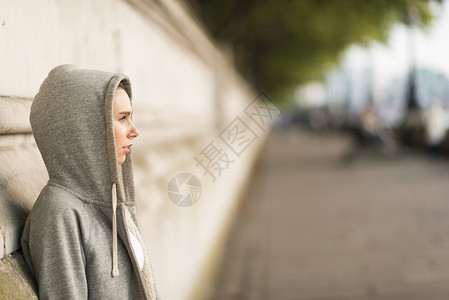穿着灰色连帽上衣的年轻女性从河边向外看图片