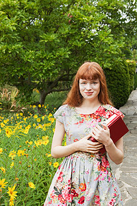 在公园里拿书的年轻女子图片