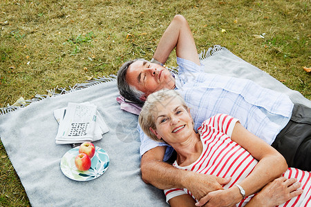 一对夫妇躺在草地上的野餐毯上图片