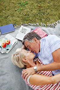 一对成熟的情侣在野餐毯上接吻图片