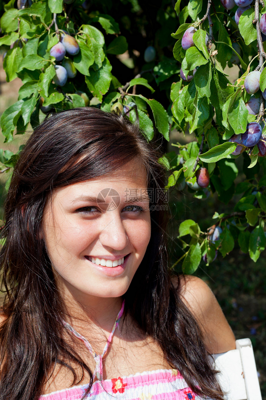 坐在果树旁微笑的女人图片