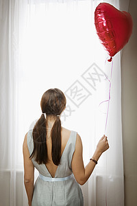 在窗户前拿着气球的女人背景图片