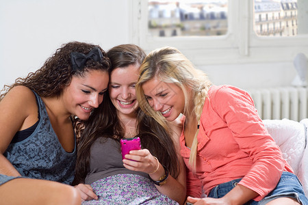 年轻女性在沙发上分享手机短信开心高清图片素材