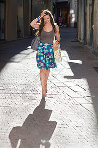 年轻女子拿着包走在街上图片