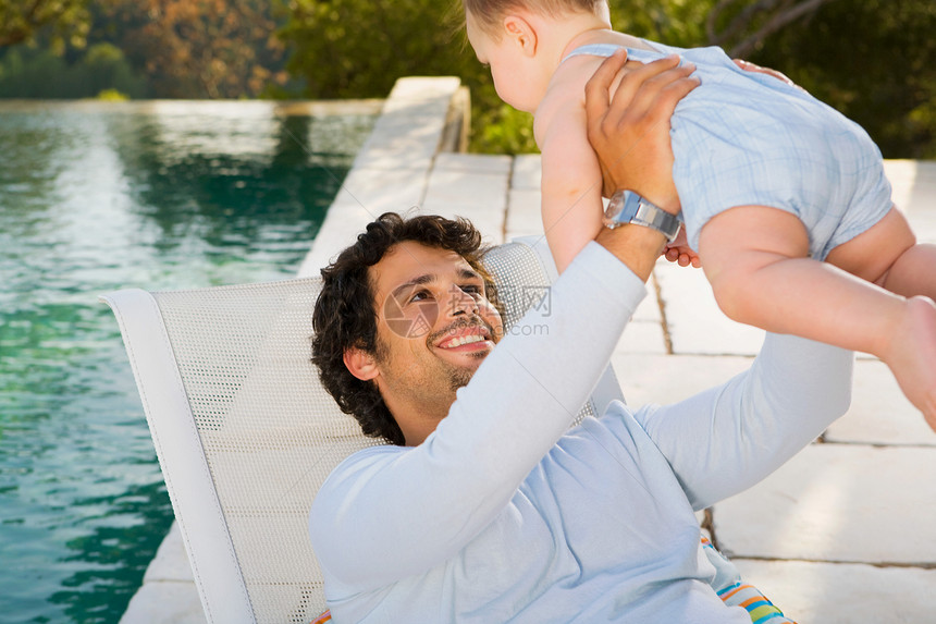 男人在泳池旁抱着婴儿图片