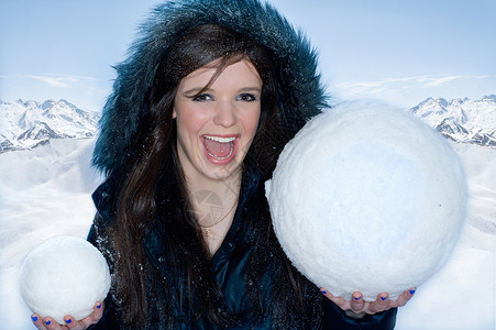 带着两个雪球的年轻快乐女人背景图片
