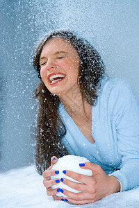 女人在雪地里笑，手里拿着雪球图片
