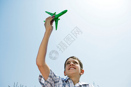 男孩举着玩具飞机在高空图片