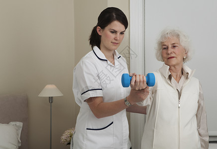 手部重量护士帮助妇女做运动背景