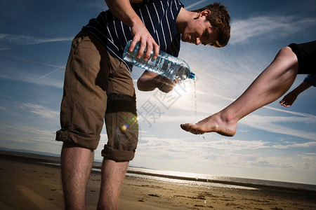 男人在沙滩上用水洗女人的脚图片