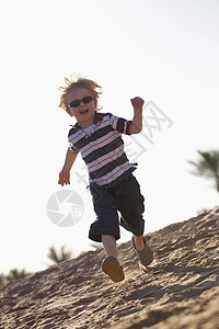 戴墨镜的男孩在海滩上跑步图片