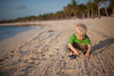 在海滩上玩沙子的小男孩背景图片