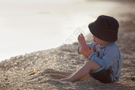 在海滩上玩沙子的小男孩背景图片