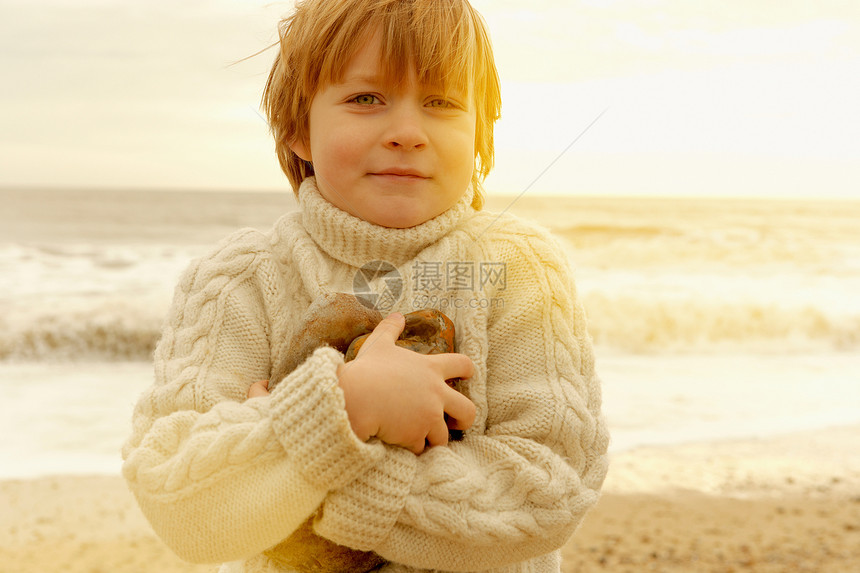 在海滩上拿着石头的小男孩