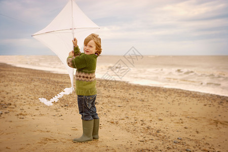 海滩上拿着风筝的小男孩开心高清图片素材